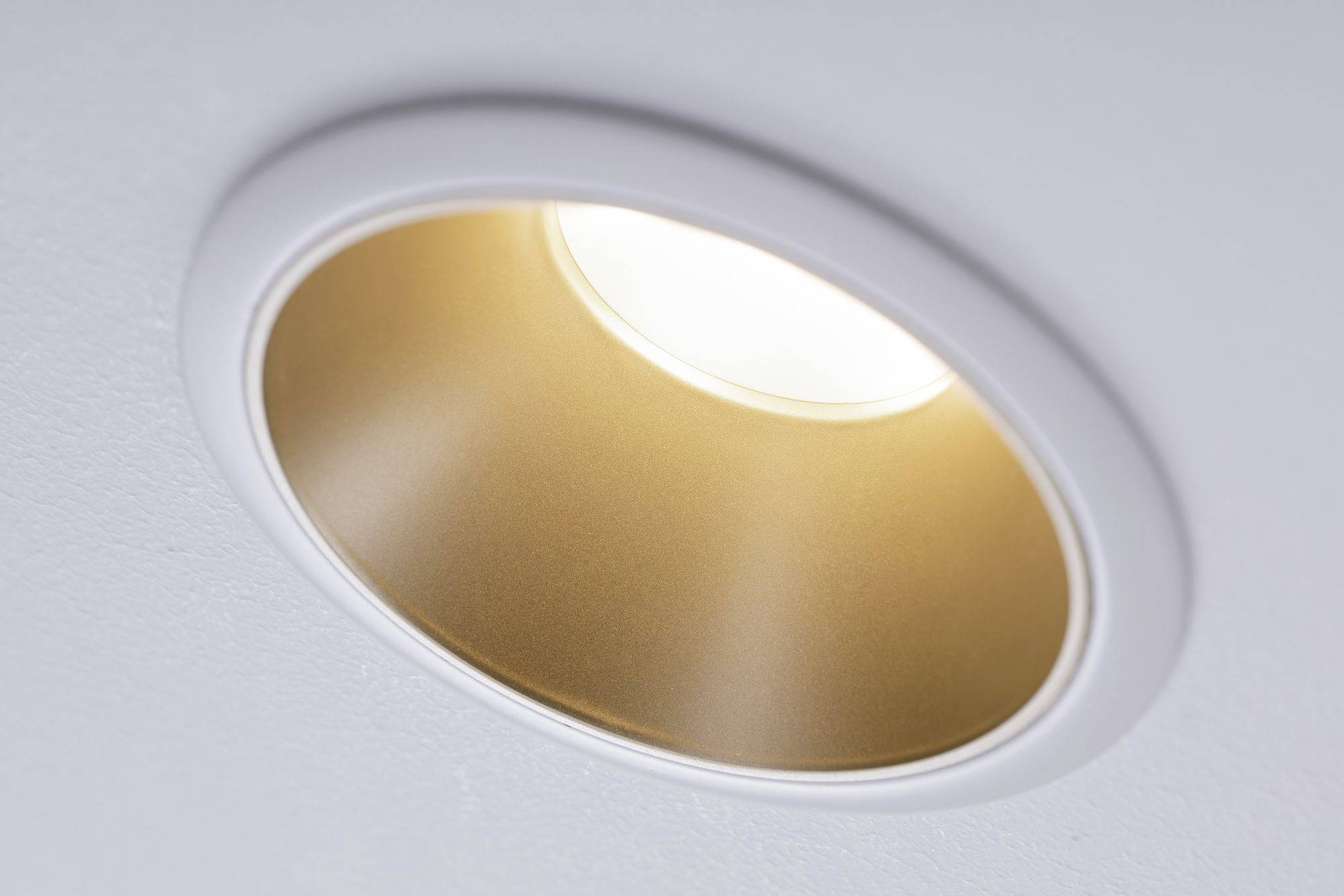 Ein eingebautes, rundes Deckenlicht leuchtet hell von oben. Die Fassung ist weiß mit goldenem Innenrand, sorgt für gleichmäßige Beleuchtung.