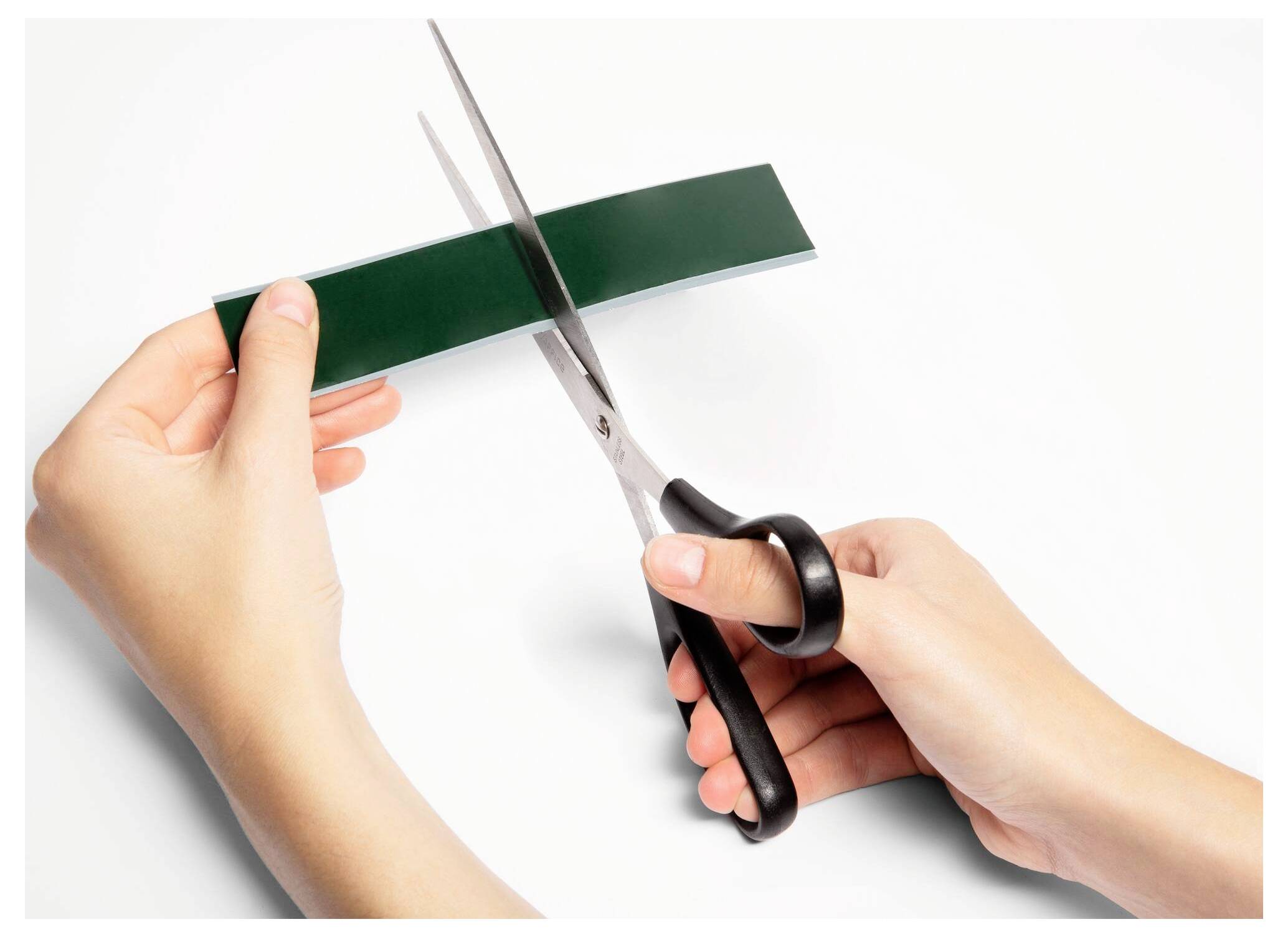 Hände, die mit einer Schere einen Streifen grünes Papier ausschneiden.