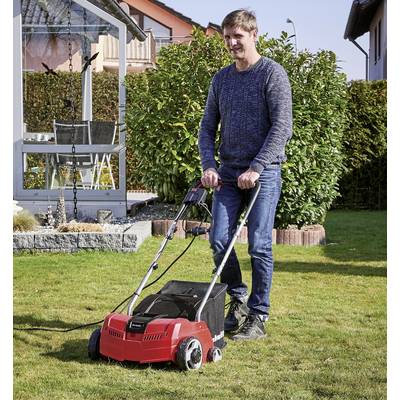 Ein Mann mäht mit einem roten Rasenmäher den Rasen in einem Garten. Im Hintergrund sind ein Haus und ein Gewächshaus zu sehen.