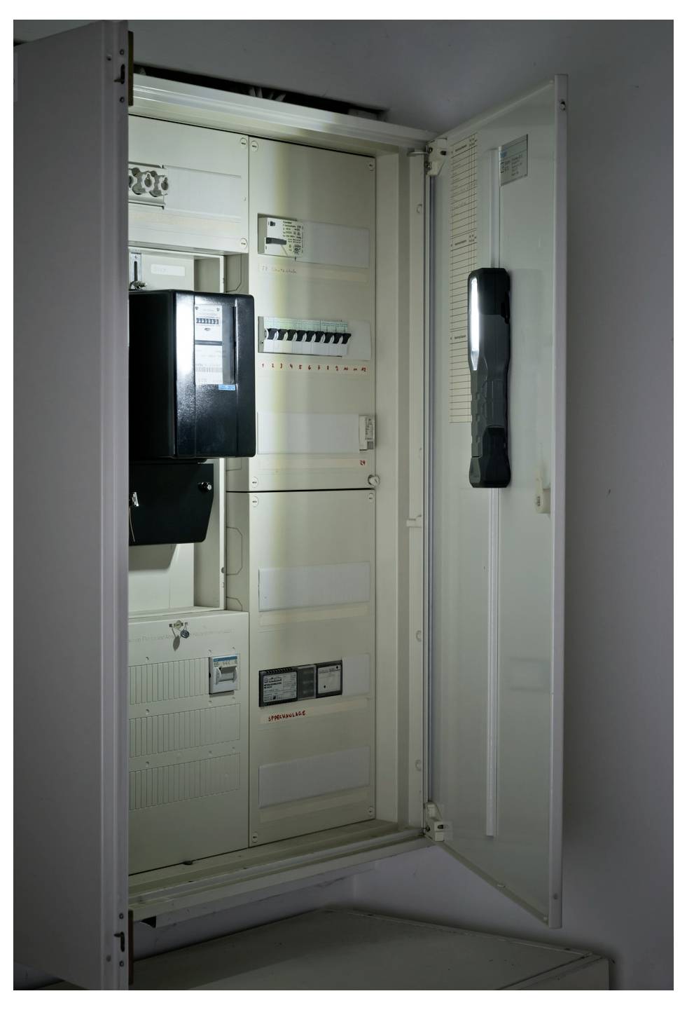 Offenes Elektrisches Bedienfeld mit Schutzschaltern und Messermodulen in einem weißen Versorgungskasten.