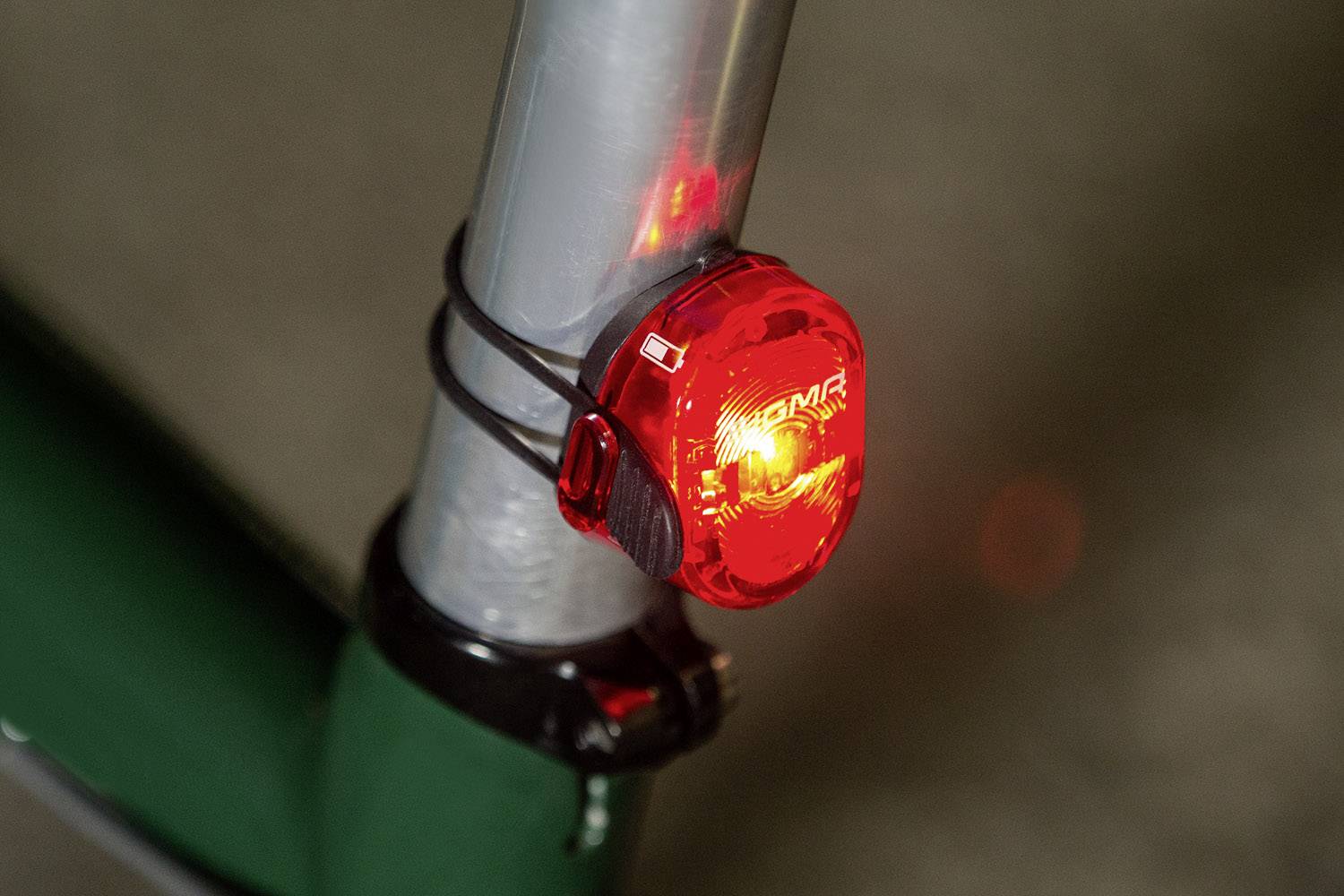 Rotes Rücklicht an einem Fahrradrahmen, befestigt mit Gummibändern, leuchtet zur Verkehrsicherheit.