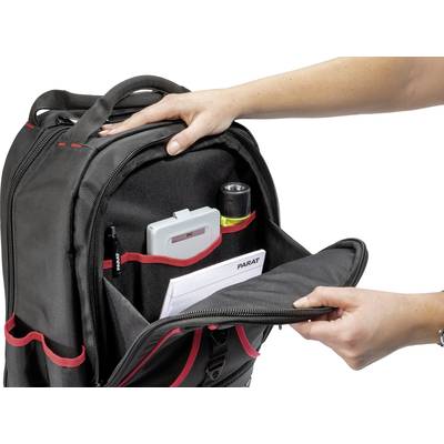 Eine Person öffnet den vorderen Teil eines schwarzen Rucksacks mit roten Akzenten, der Taschen und gefüllte Fächer zeigt.