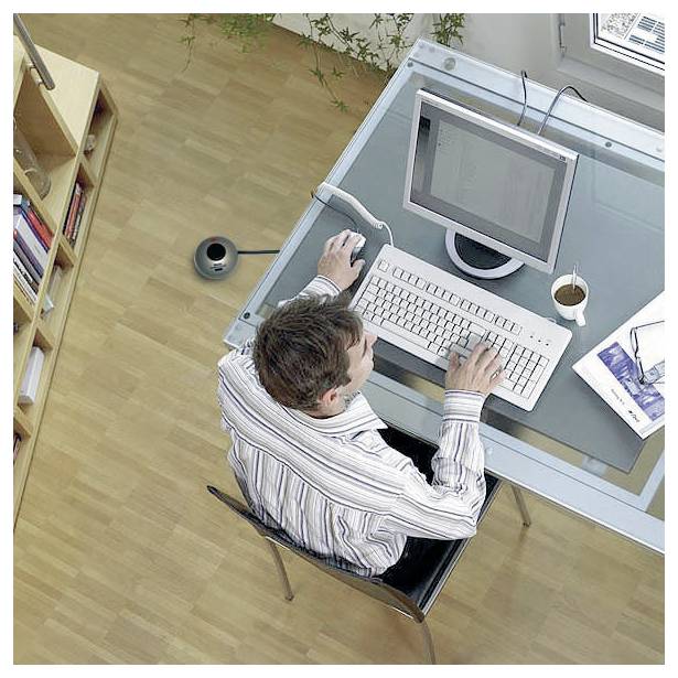 Oberansicht eines Mannes, der an einem Schreibtisch mit einem Computer, einer Tastatur, einer Maus und einer Kaffeetasse in einer hellen Büroumgebung tippt.