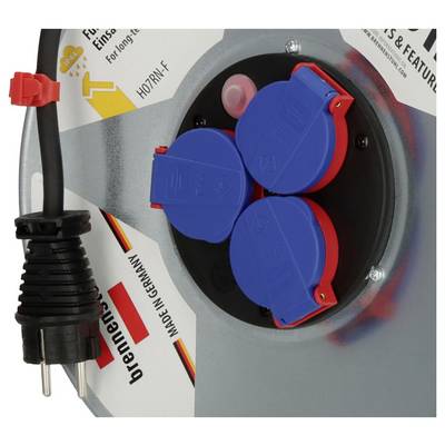 Nahaufnahme eines industriellen Elektroschaltschranks mit einer blauen Dreifach-Steckdose mit roten Abdeckungen und einem angebrachten robustem Stecker auf der linken Seite.