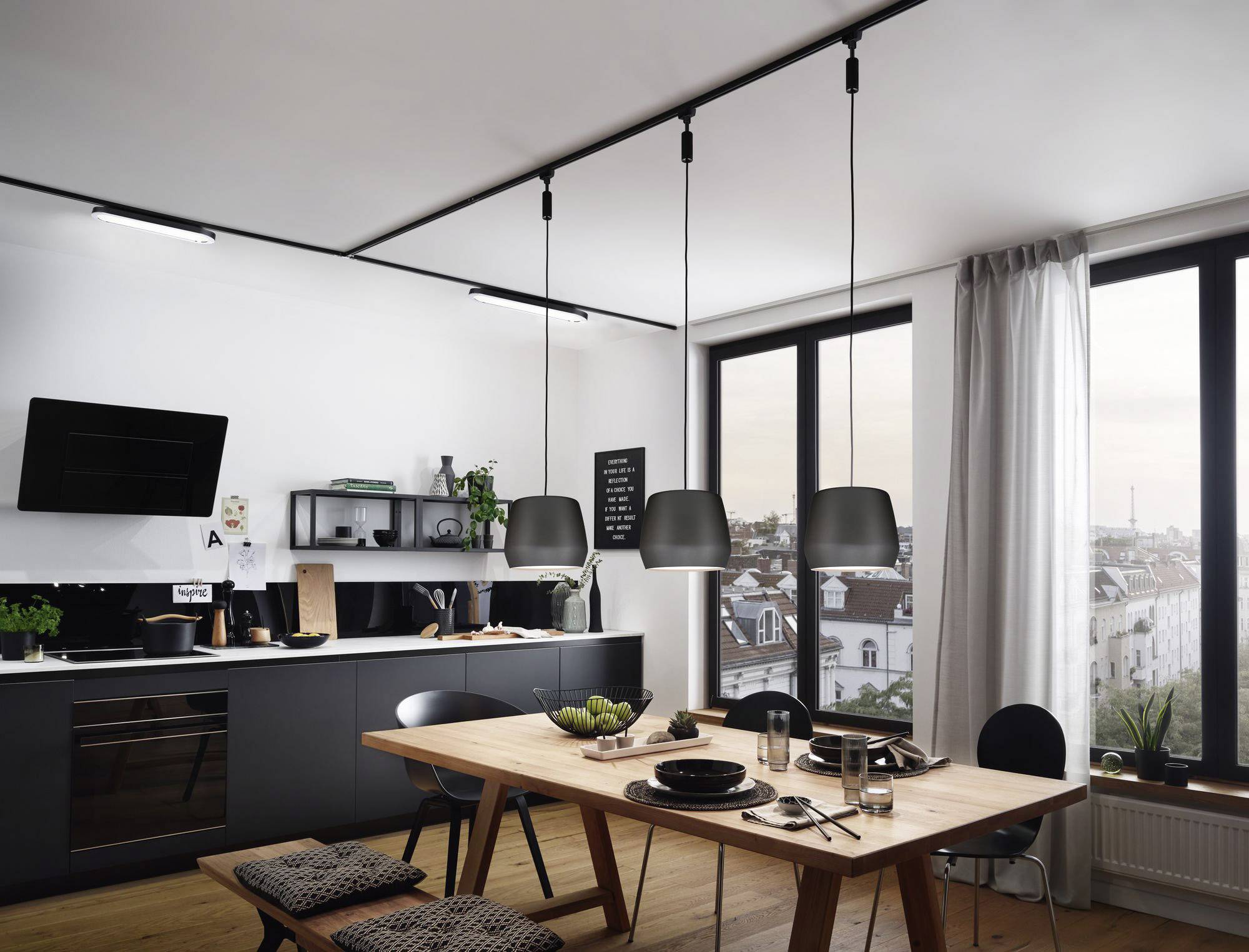 Moderne Küche mit Esstisch und Hängelampen, blick auf Stadtsilhouette durch große Fenster. Schlichte Möbel in dunklen Tönen.