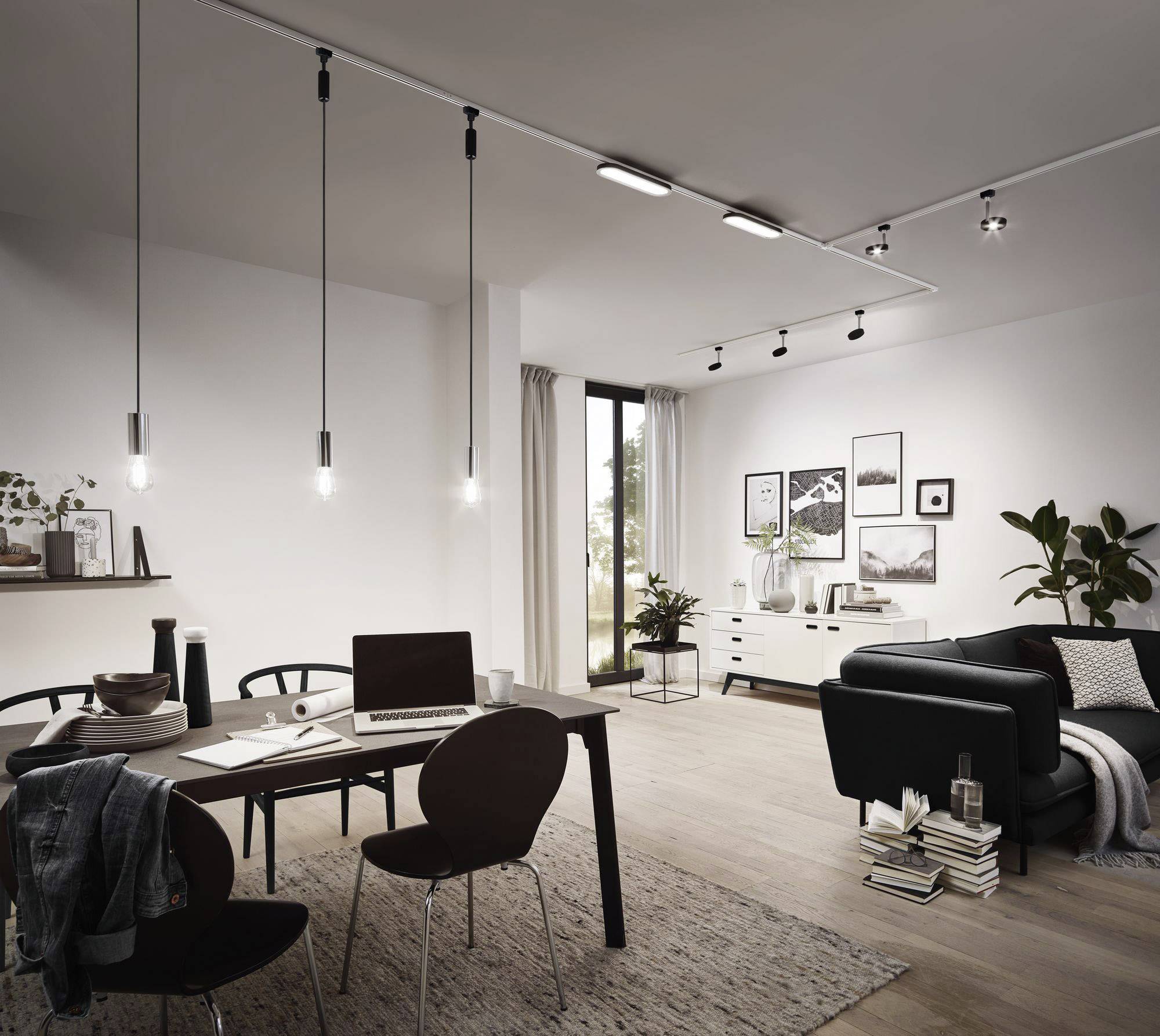 Modern eingerichtetes Wohnzimmer mit Esstisch, schwarzem Sofa, Dekorpflanzen und Wandbildern. Große Fenster lassen viel Licht herein.