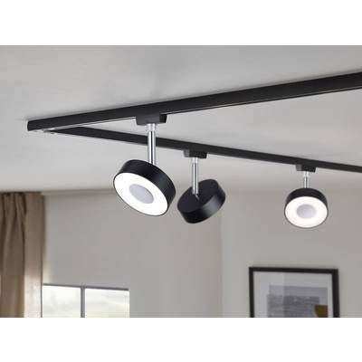 Schwarzes Schienensystem mit drei runden, verstellbaren Deckenleuchten an einer weißen Decke in einem modern eingerichteten Raum.