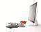 Ein Desktop-Monitor und eine Tastatur auf weißem Tisch, daneben liegen drei rote Äpfel; modernes und minimalistisches Büroszenario.