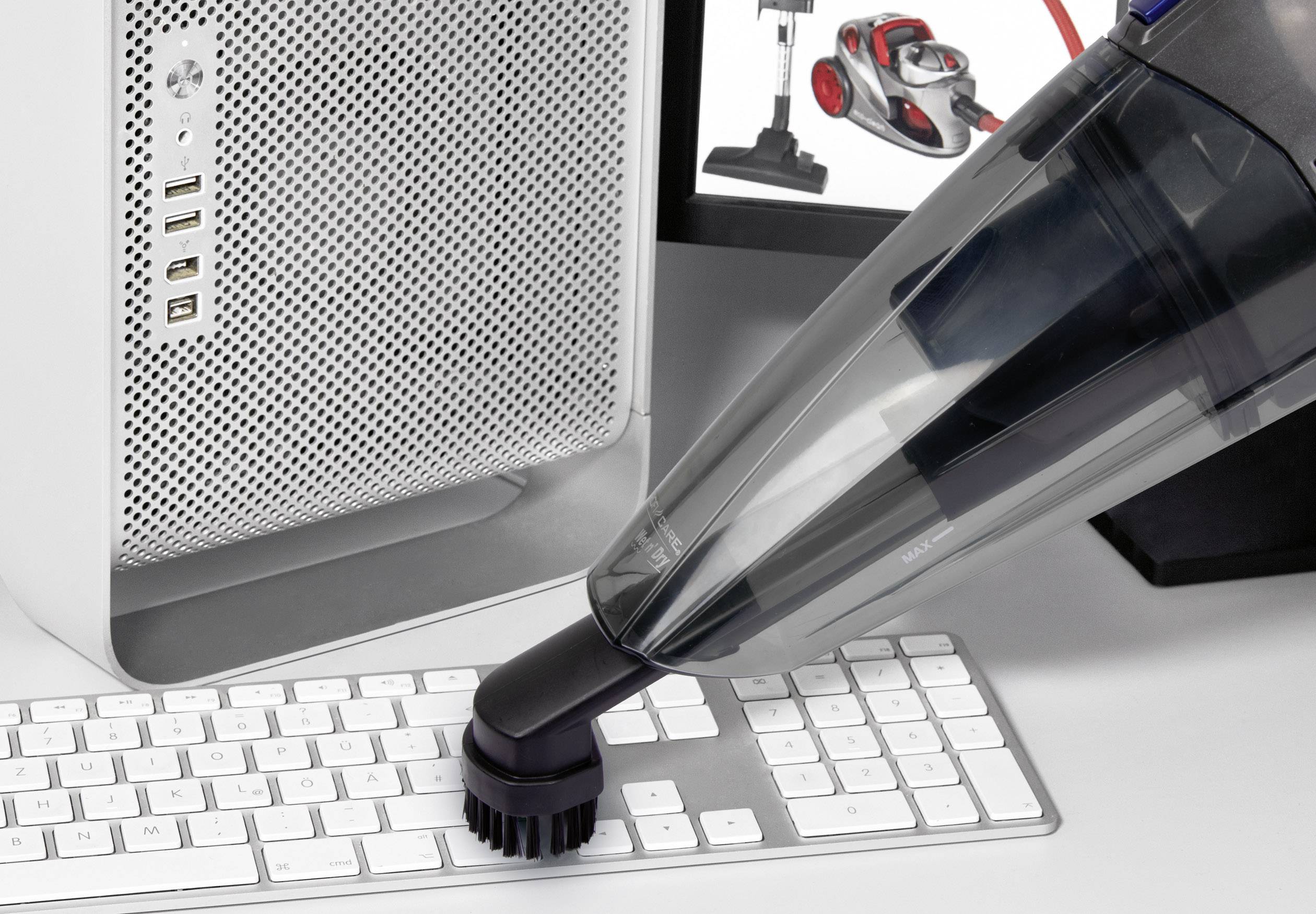 Ein Handstaubsauger reinigt eine Computertastatur vor einem Bildschirm, der verschiedene Staubsaugermodelle zeigt.