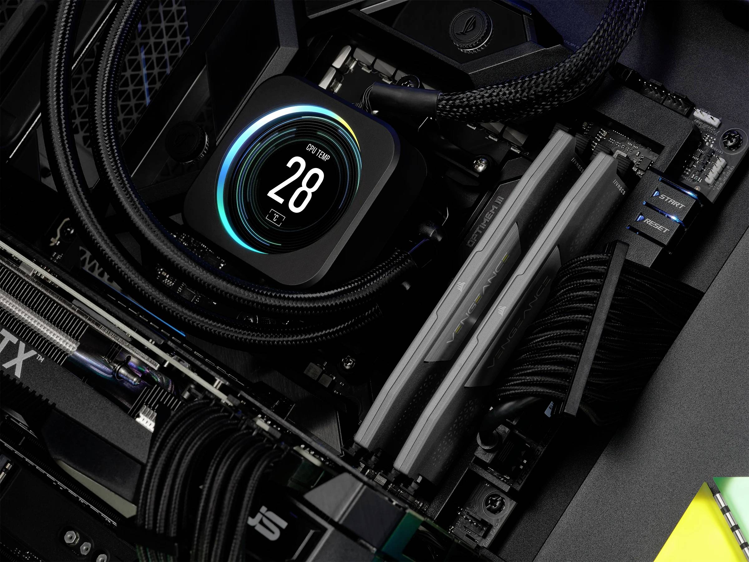 Computer-Innenansicht zeigt eine Wasserkühlungseinheit mit digitaler Anzeige '28°C'. Auf der Hauptplatine sind RAM-Module installiert.