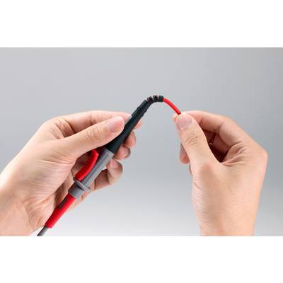 Eine Person hält ein rotes Kabel mit zwei Händen, wobei eine Hand das Ende mit einem Stecker umfasst.