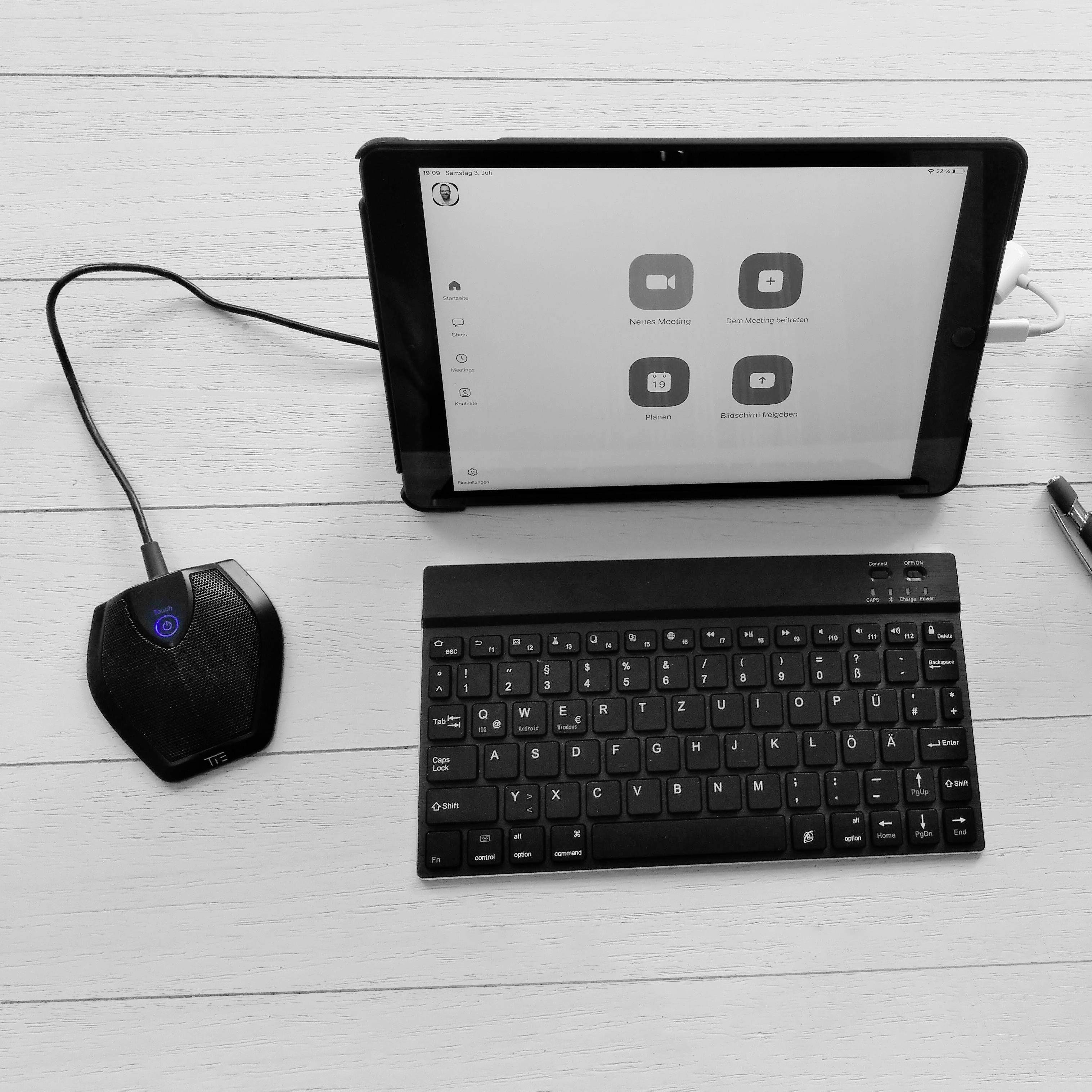 Ein Tablet zeigt ein Kontrollzentrum mit verbundenen Geräten, darunter ein Audiogerät links und eine Bluetooth-Tastatur davor.