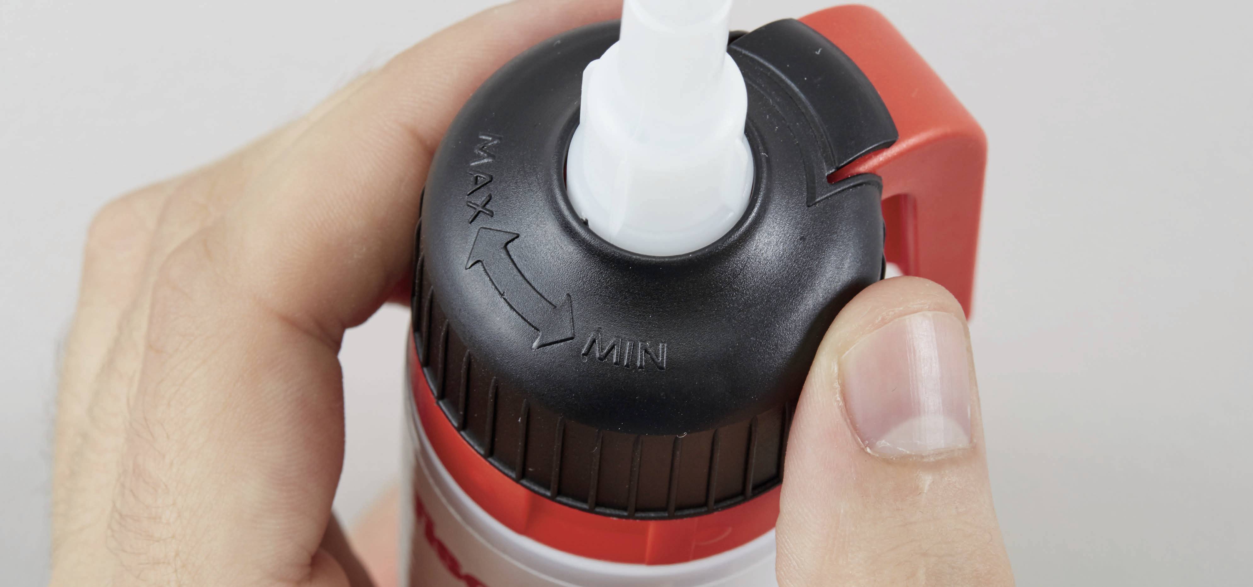Eine Hand dreht den Verschluss eines Hygieneprodukts mit Aufschrift 'MAX-MIN', um die Öffnungseinstellung zu verändern.