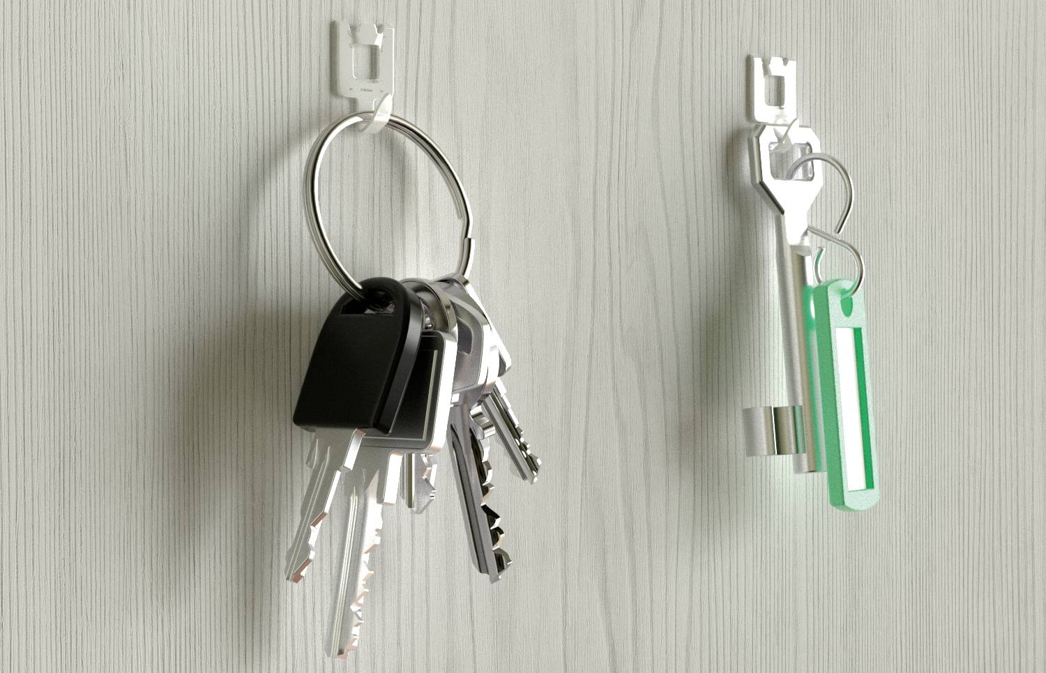 Ein Schlüsselbund mit mehreren Schlüsseln hängt links an einem Haken. Rechts hängt ein einzelner Schlüssel mit einem grünen Anhänger.