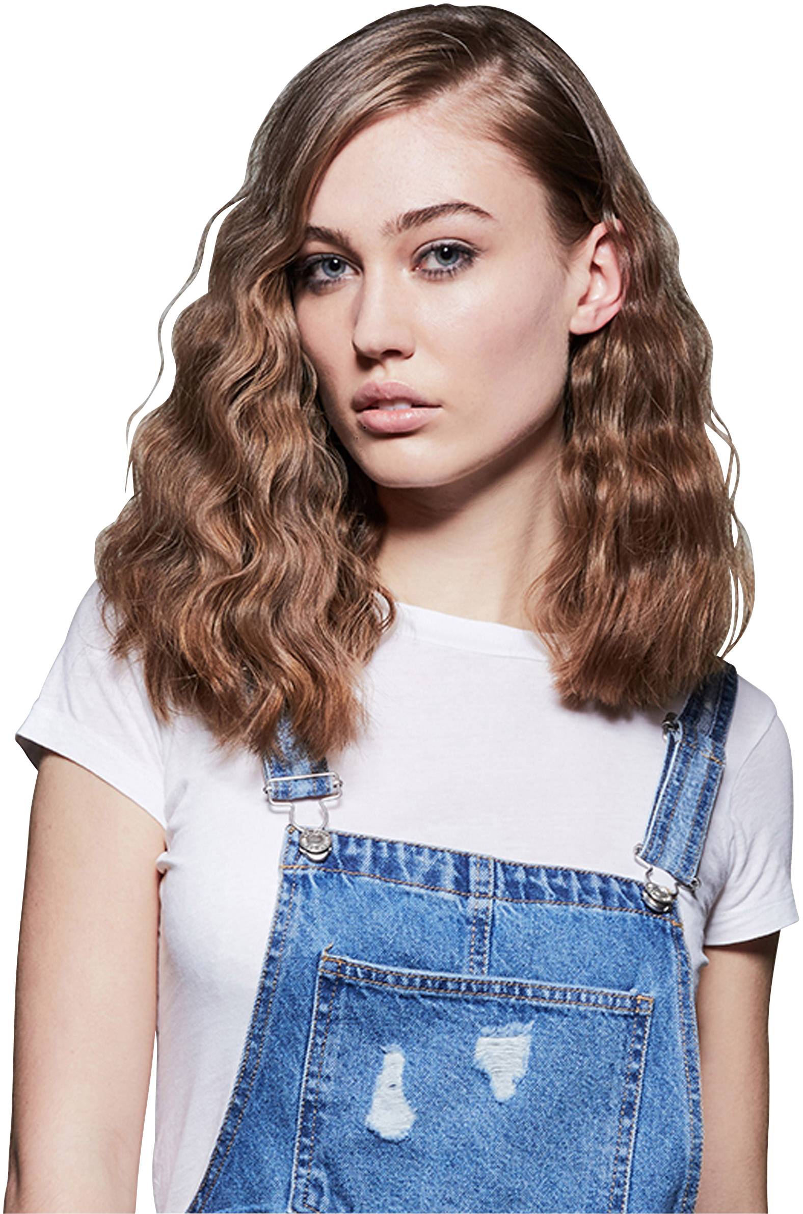 Eine junge Frau mit welligem Haar trägt ein weißes T-Shirt und einen blauen Jeansoverall.