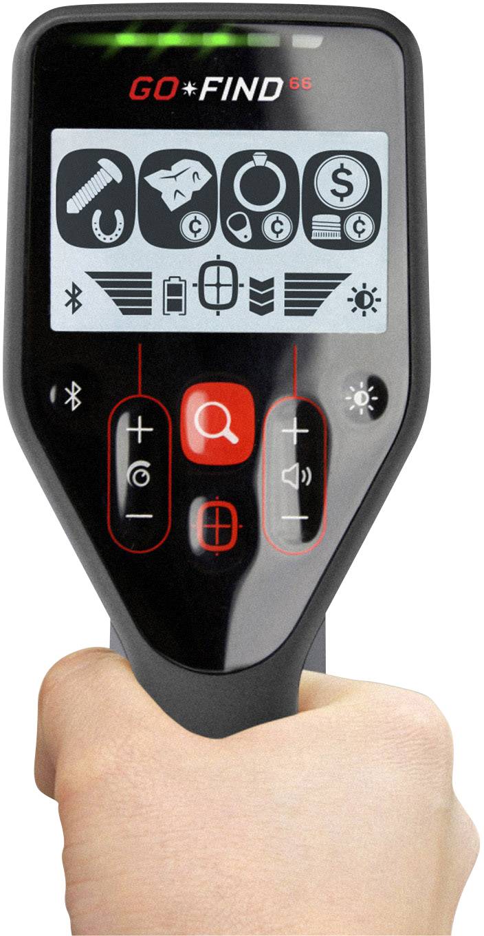 'Hand hält ein Metalldetektor mit Display. Symbole zeigen Werkzeuge, Fisch, Ring, Dollarseichen und Lichter. Rote Tasten zur Steuerung.'