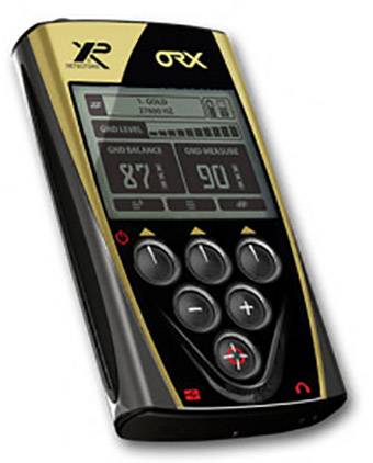 Ein gold-schwarzes tragbares Gerät mit digitalen Anzeigen und fünf Tasten. Der Bildschirm zeigt 'GOLD' und andere Messinformationen.