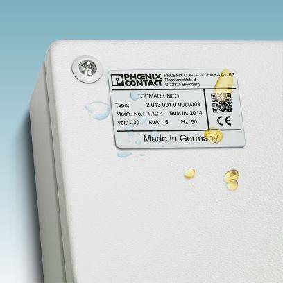 Ein weißes Gerät mit einem Etikett von 'PHOENIX CONTACT', Modell 'TOPMARK NEO', technische Spezifikationen und Angabe 'Made in Germany'.