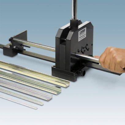 Hand drückt auf Metallstanzmaschine, um Metallstangen in gleichmäßige Stücke zu schneiden. Mehrere geschnittene Metallstangen liegen daneben.