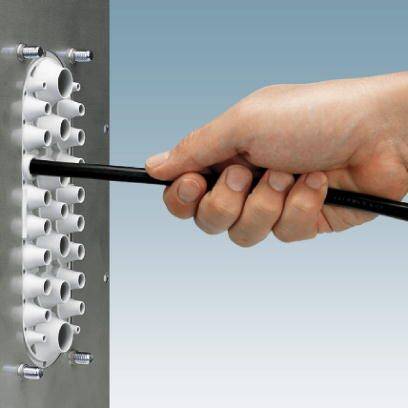 Hand steckt ein schwarzes Kabel in eine metallische Kabelbuchse mit mehreren Öffnungen. Technikmontage oder Netzwerkinstallation.