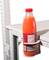 Eine rote Saftflasche in einem Halter an der Kante eines weißen Tisches befestigt, zeigt das Etikett.