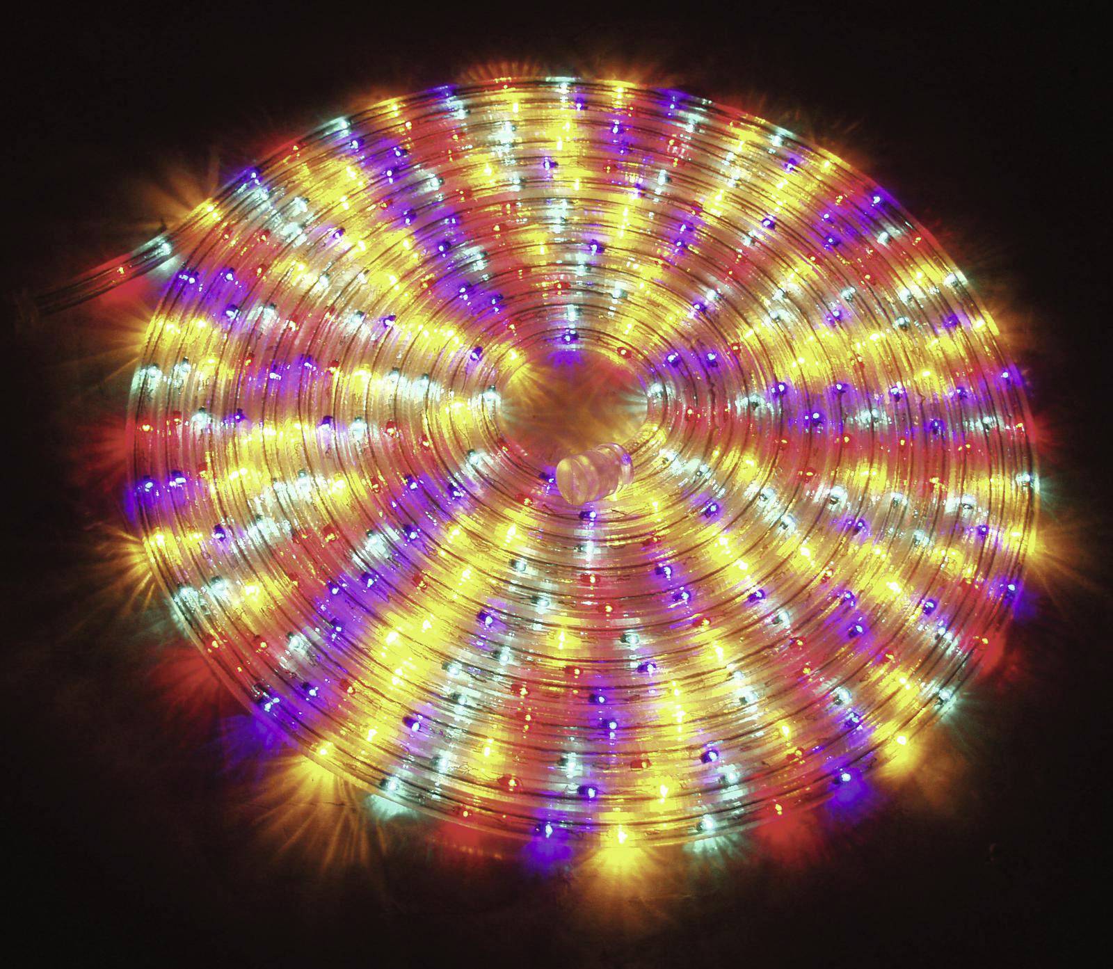 Bunte LED-Leuchtkabel in spiralförmigem Muster auf schwarzem Hintergrund, strahlend in Rot, Blau und Gelb.