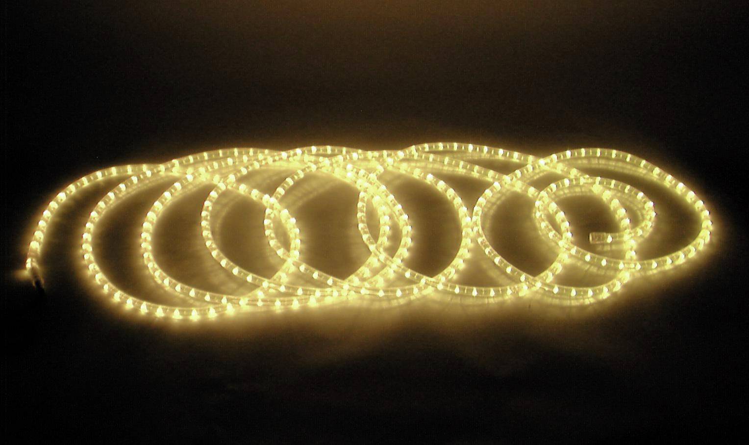 Ein gelber LED-Lichtstreifen, spiralförmig auf dem Boden angeordnet, leuchtet in einem dunklen Raum und schafft eine warme Atmosphäre.