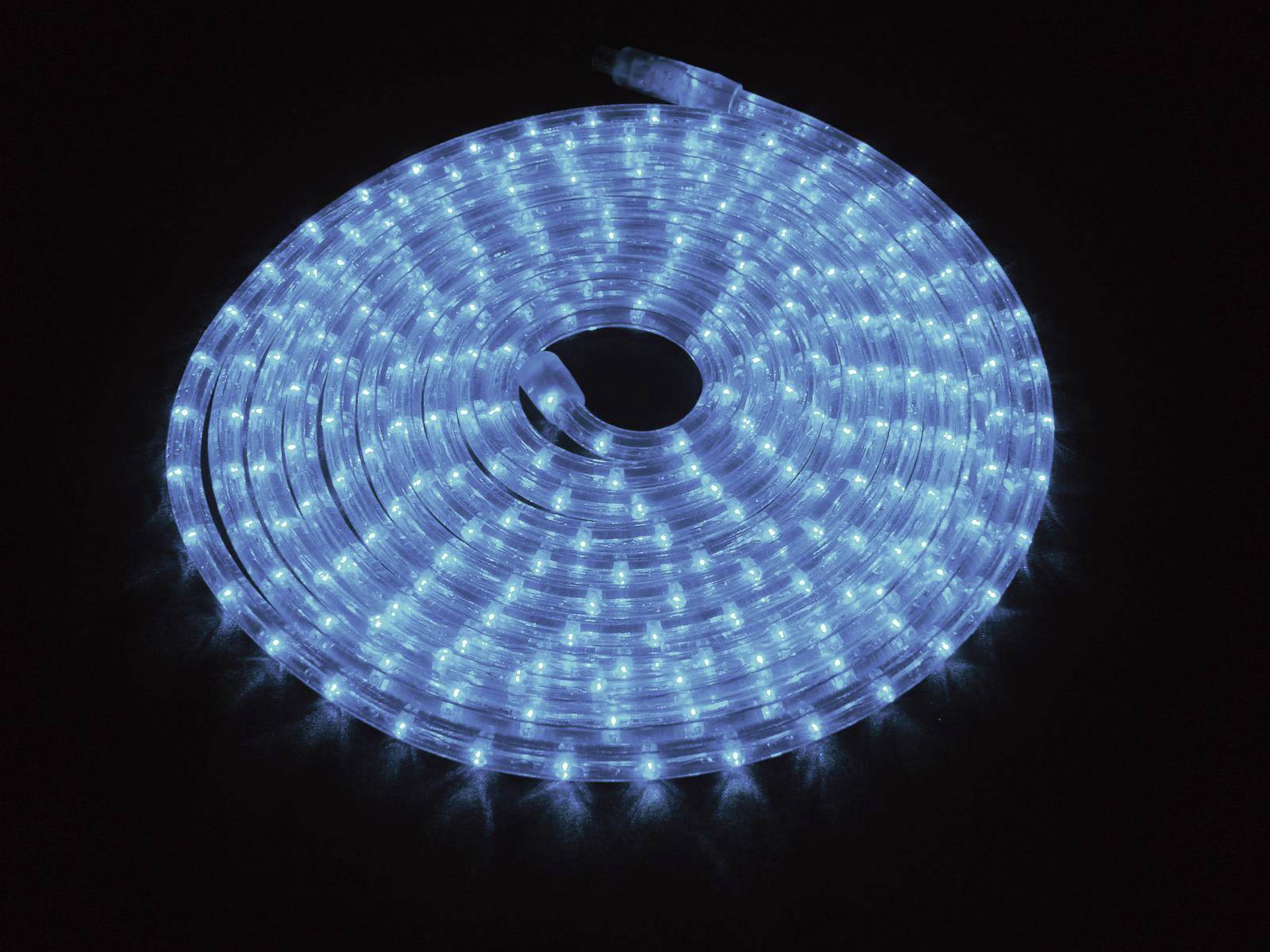 Eine aufgerollte, blaue LED-Lichterkette leuchtet hell auf einem dunklen Hintergrund. Sie verbreitet ein kühles, gleichmäßiges Licht.