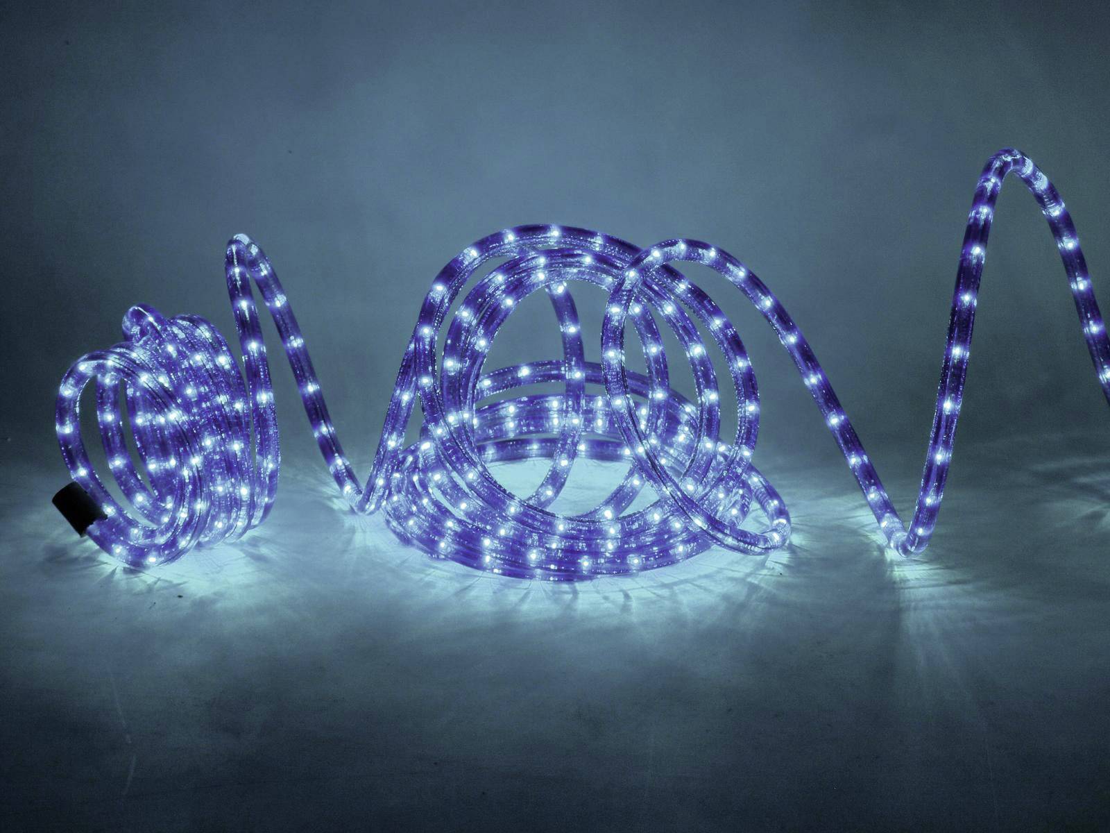 Blaue LED-Lichtstreifen in verschiedenen spiralförmigen Anordnungen leuchten auf einem dunklen Hintergrund.
