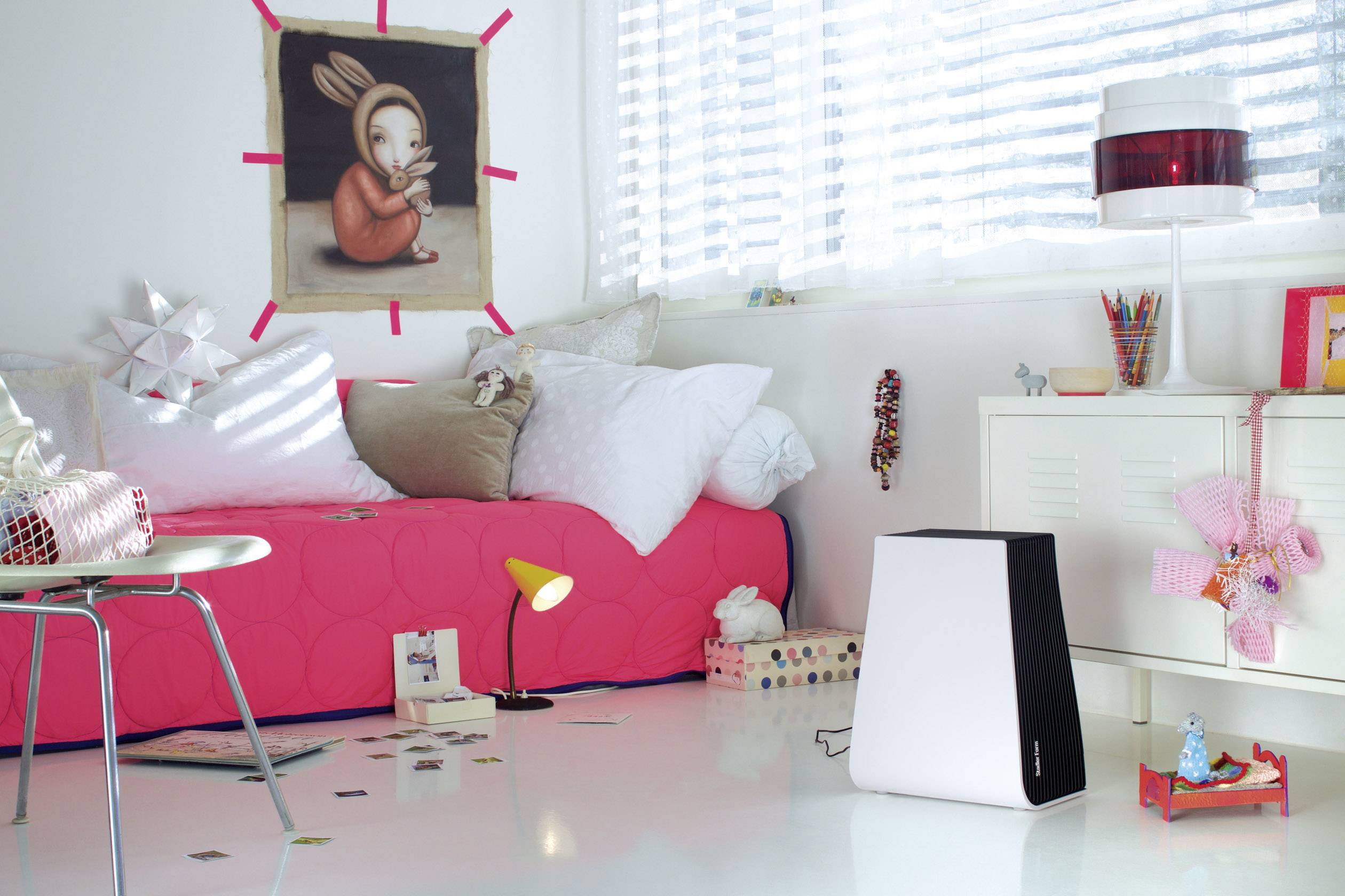 Ein stilvolles Kinderzimmer mit einem roten Bett, buntem Kunstwerk an der Wand und künstlerisch gestreuten Spielsachen auf dem Boden.