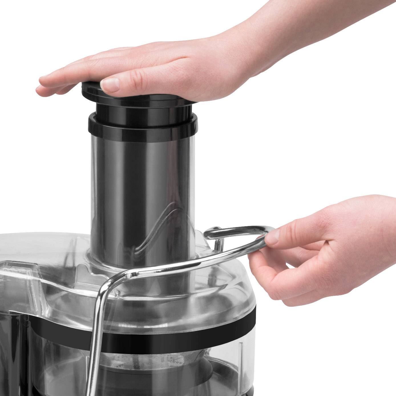 Eine Person drückt Früchte in eine Entsaftermaschine mit ihren Händen.