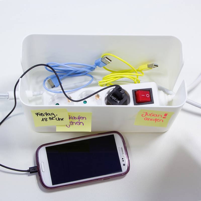 Ein Smartphone wird über ein USB-Kabel an eine Steckdosenleiste angeschlossen. Notizen zeigen geplante Aufgaben: '18:30 Uhr kaufen gehen', 'Juxlan anrufen'.