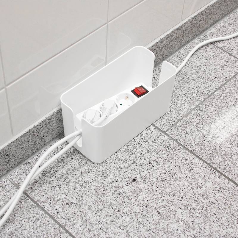 Kabelbox auf Boden mit Mehrfachsteckdose und mehreren eingesteckten Kabeln; Box organisiert und schützt Kabel vor Unordnung.