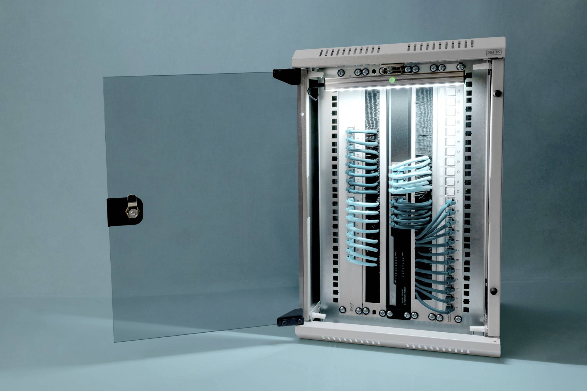 'Offener Serverschrank mit ordentlich verlegten blauen Netzwerkkabeln, die an Patchpanels angeschlossen sind, vor blauem Hintergrund.'