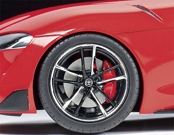 Nahaufnahme eines roten Sportwagens mit glänzendem schwarzen Reifen und silbernen Felgen. Sichtbar ist das Logo in der Mitte der Felge.