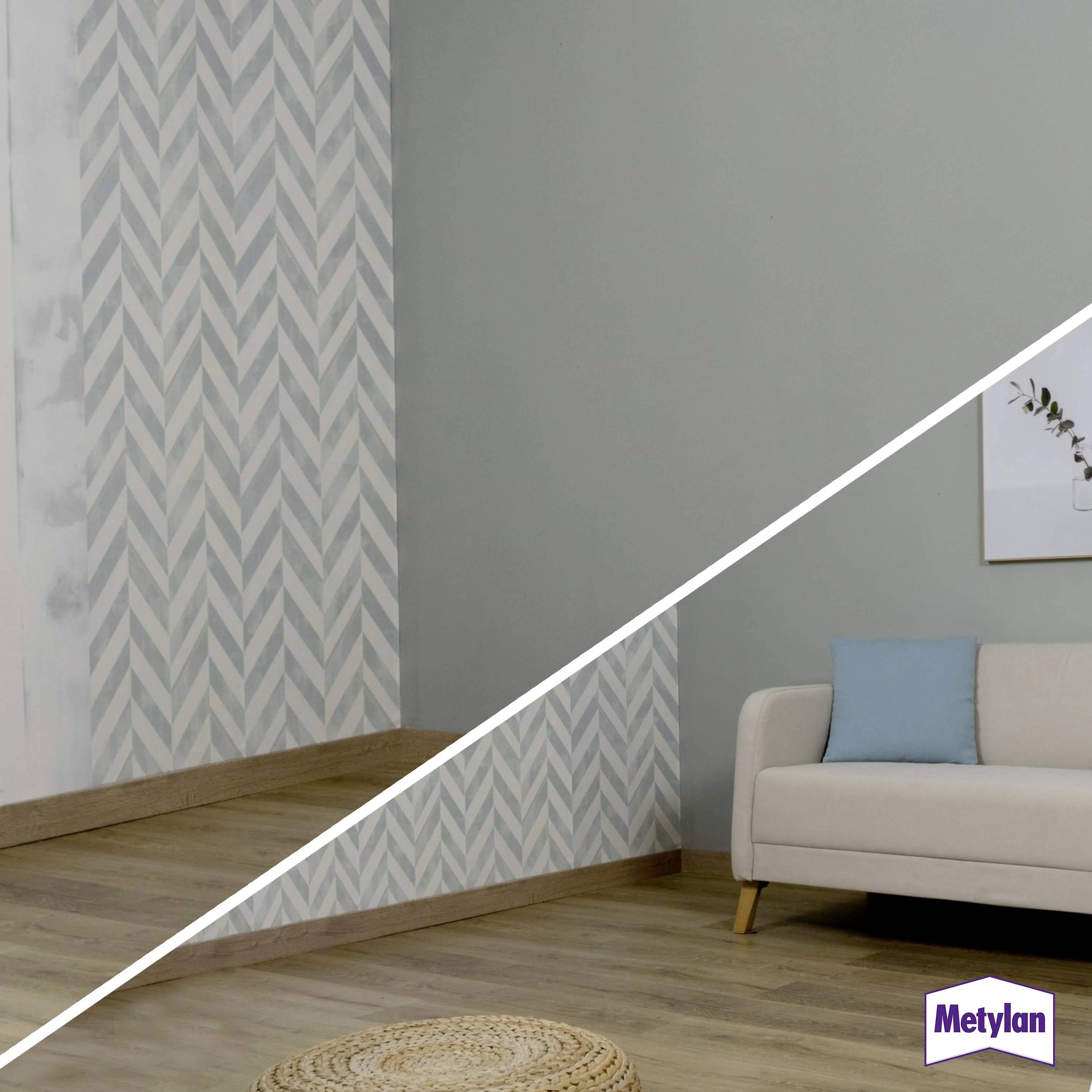 Ein Wohnzimmer zeigt links eine Wand mit Zickzackmuster-Tapete und rechts eine glatte, graue Wand. Ein Sofa steht vor der grauen Wand. Metylan Logo unten rechts.