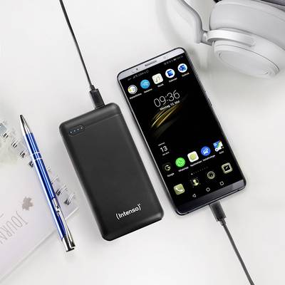 Smartphone und Powerbank laden nebeneinander. Ein Notizbuch und ein Kugelschreiber liegen daneben. Kopfhörer in der Ecke sichtbar.