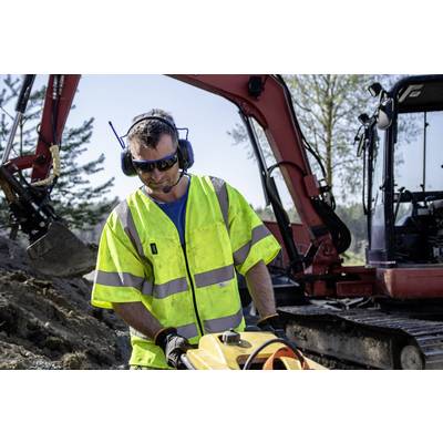 Ein Bauarbeiter in gelber Warnkleidung arbeitet mit einem Werkzeug vor einem Bagger auf einer Baustelle im Freien.