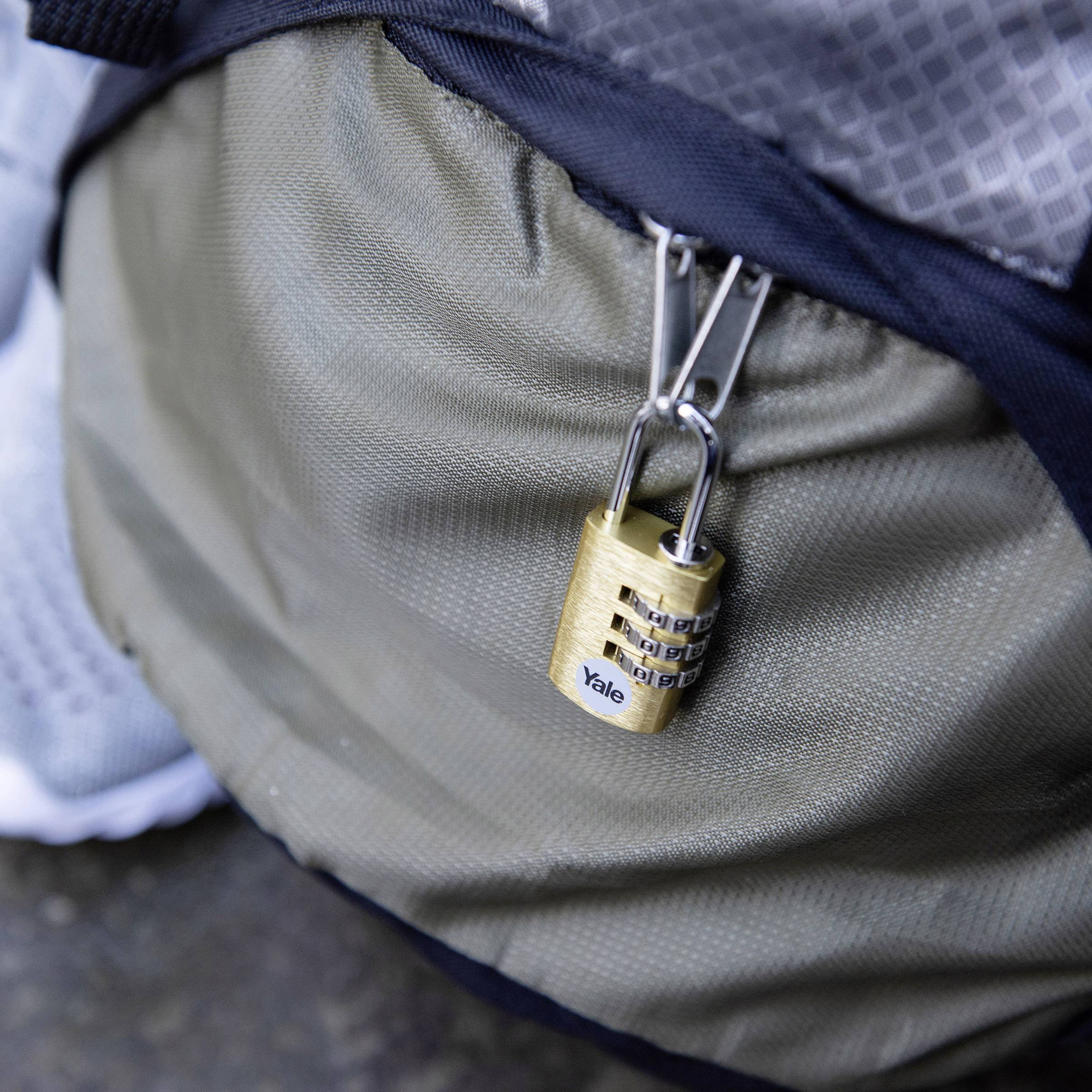 Ein grauer Rucksack mit einem Vorhängeschloss an einem Reißverschluss. Das Schloss ist geschlossen und hat die Aufschrift 'Yale'.