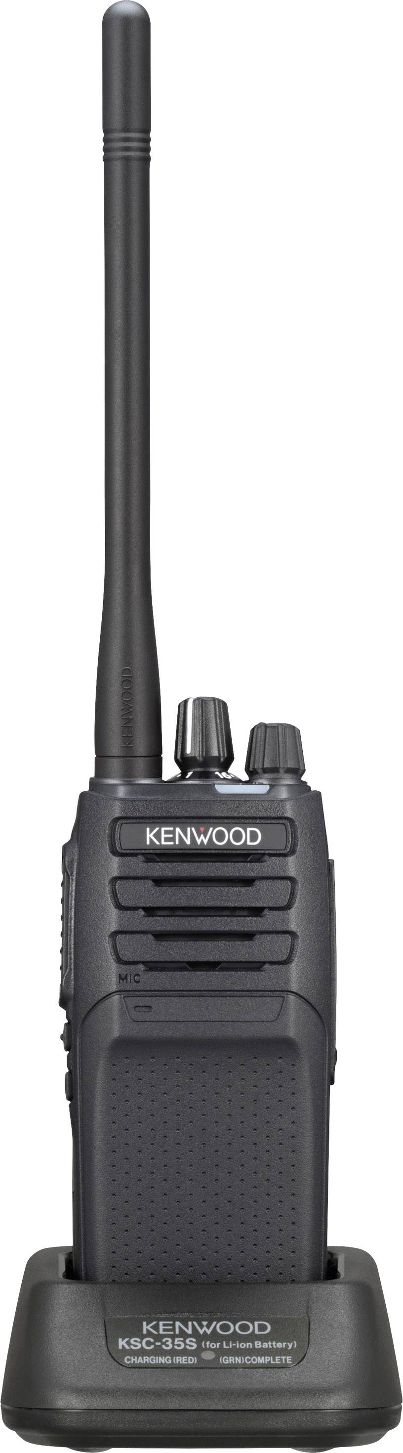 Ein tragbares Funkgerät mit Antenne steht in einer Ladestation. Es trägt die Aufschrift "Kenwood" und hat mehrere Bedienknöpfe.