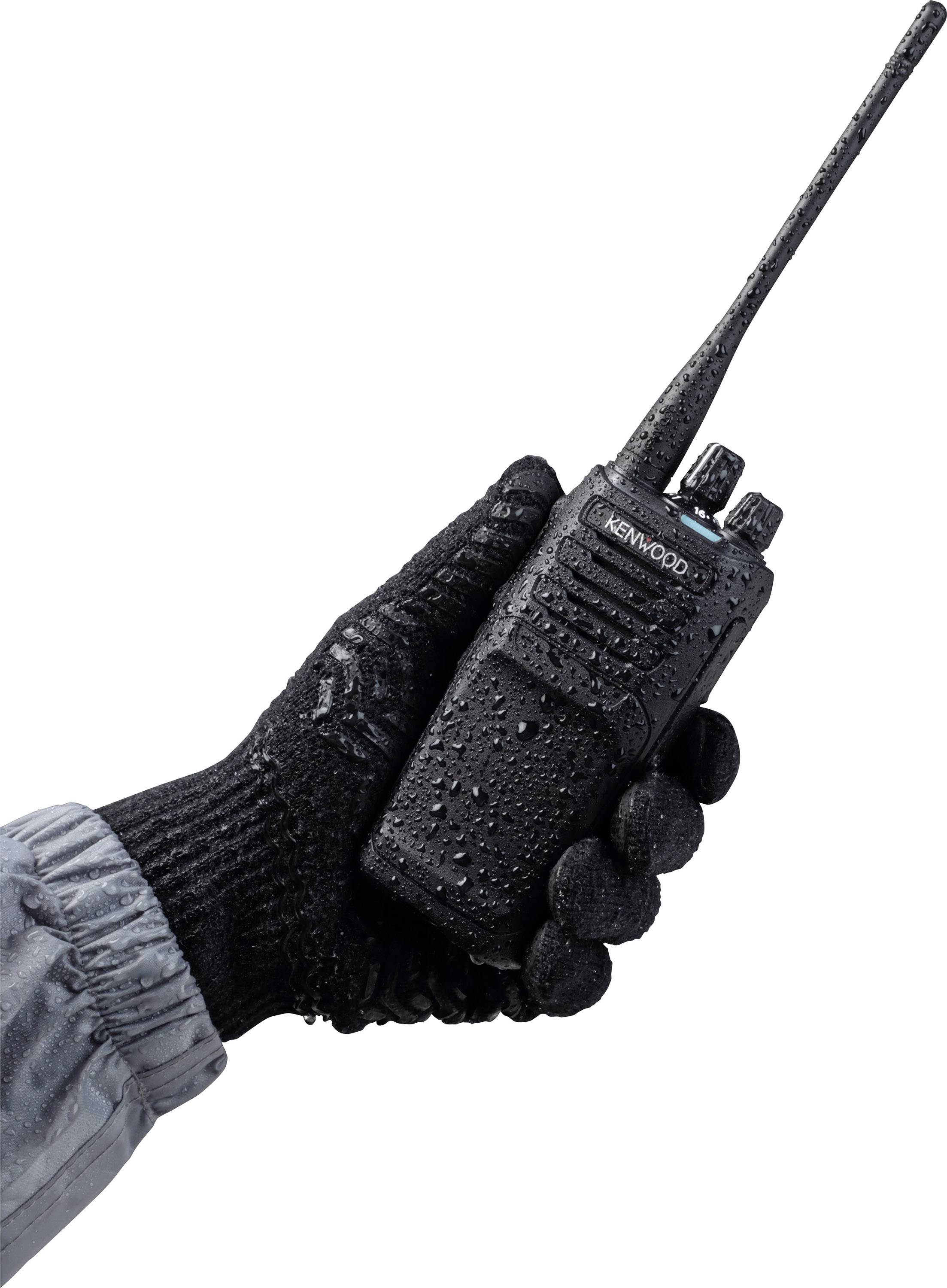 Eine Hand in einem schwarzen Handschuh hält ein schwarzes Funkgerät, das mit Wassertröpfchen bedeckt ist.