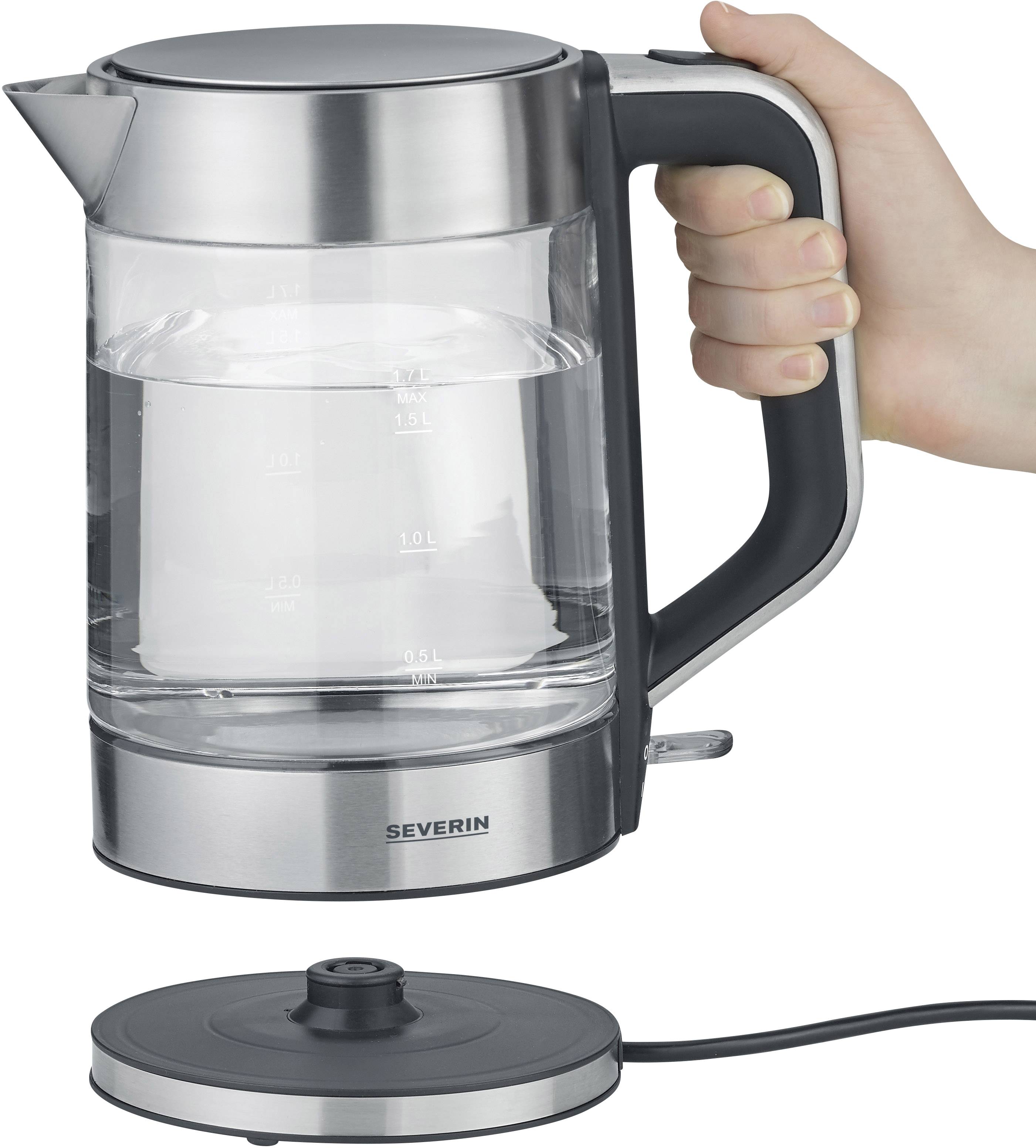 Eine Hand hält einen elektrischen Wasserkocher aus Glas mit einer Edelstahlbasis. Der Kocher steht neben seiner Basisstation.