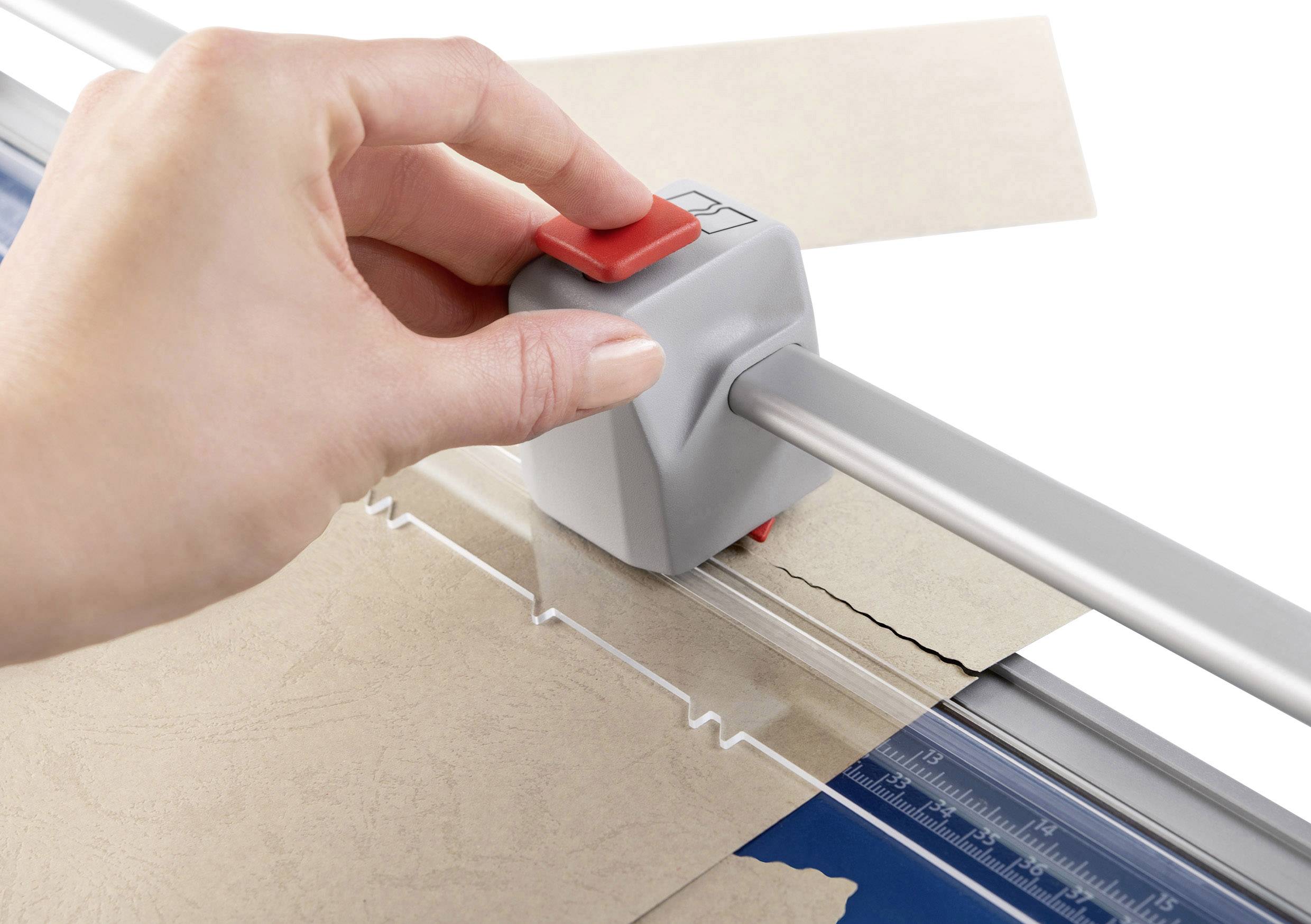 Eine Hand bedient einen Papierschneider, um einen Karton zu schneiden. Der Schneider hat eine rote Schneidevorrichtung auf einer Metallschiene.