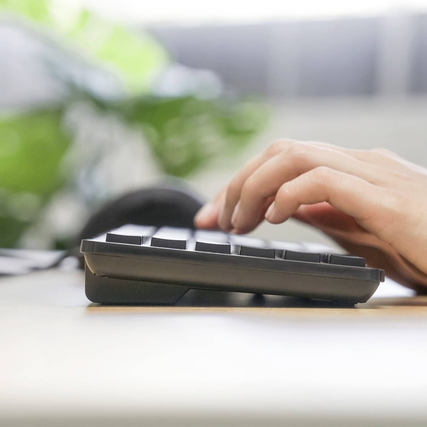 Eine Hand tippt auf einer Computertastatur vor verschwommenem Hintergrund.