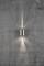 Eine Wandlampe auf einer Betonwand, strahlt Licht nach oben und unten, erzeugt dabei eine asymmetrische Lichtverteilung.