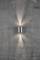 Wandleuchte an rauer Betonwand, strahlt Licht nach oben und unten, Schattenspiele auf der Wand verleihen dem Raum eine moderne Atmosphäre.
