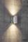 Eine Wandlampe wirft warmes Licht nach oben und unten auf eine raue Betonwand, schafft eine einladende Atmosphäre.