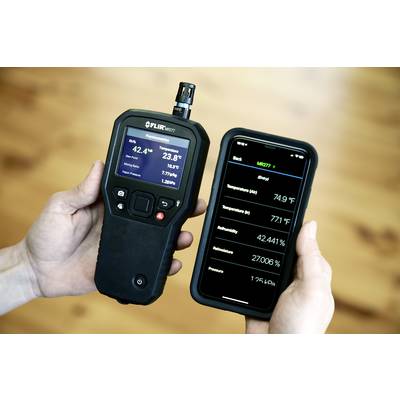 Eine Person hält ein Handgerät und ein Smartphone. Das Handgerät zeigt CO2-Werte und Temperatur an, während das Smartphone ähnliche Messdaten anzeigt.