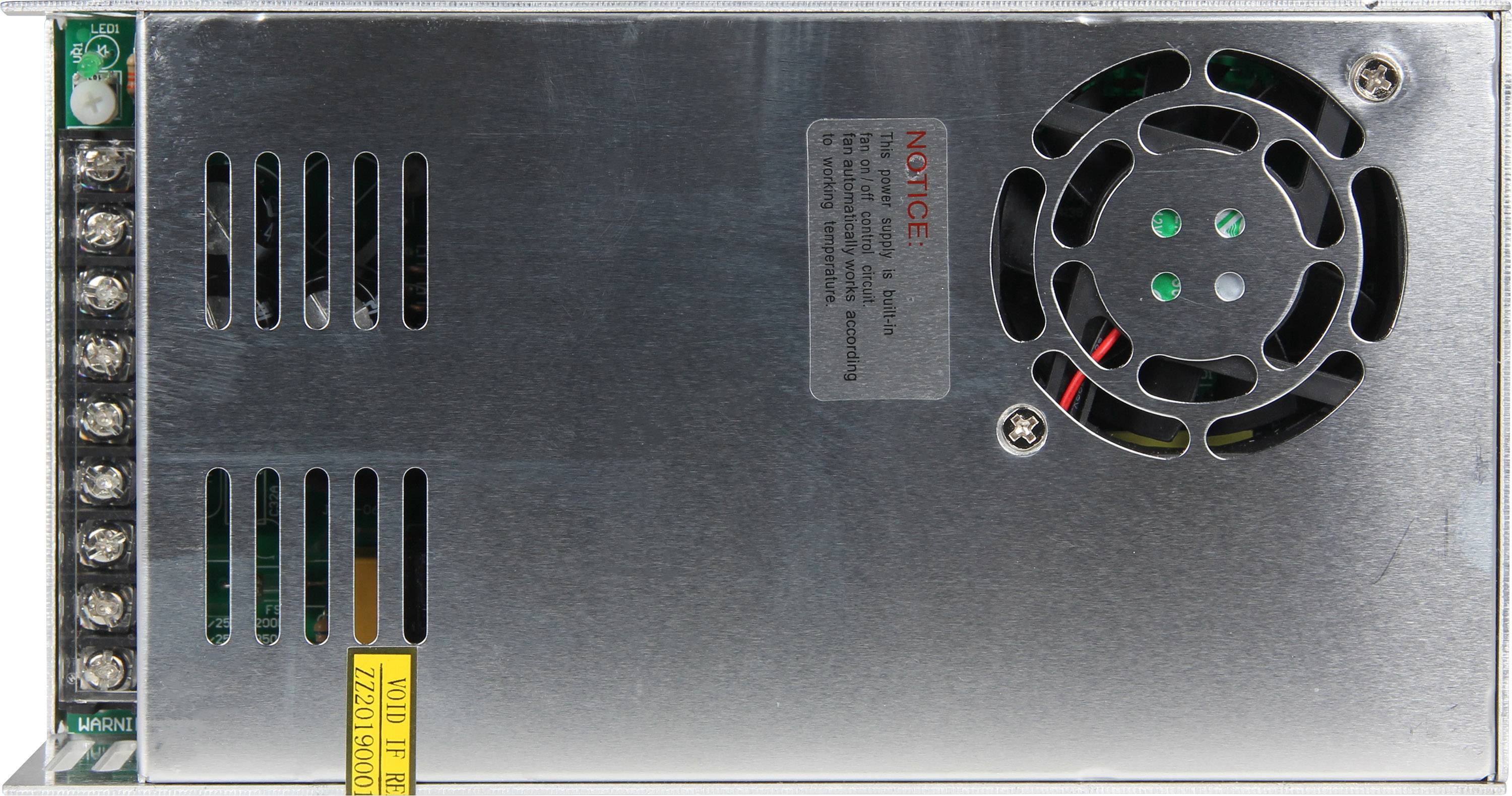 Ein rechteckiges, metallisches Netzteil mit Lüfter und Kabelanschlüssen. Ein Warnhinweis ist auf der Oberseite sichtbar.