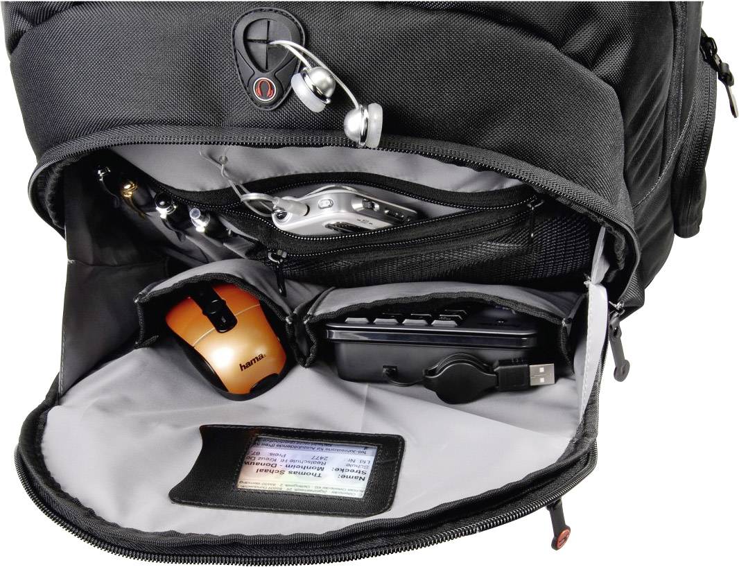 Ein offener Rucksack zeigt mehrere elektronische Geräte: ein oranger Maus, ein Ladegerät, Kopfhörer und ein Taschenrechner.